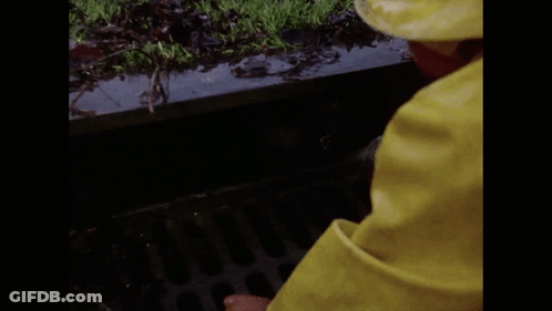 A Clown In A Yellow Raincoat Is Peeking Out Of A Drain And Says Halo GIF