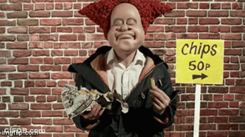 A Clown Is Eating Chips In Front Of A Brick Wall GIF