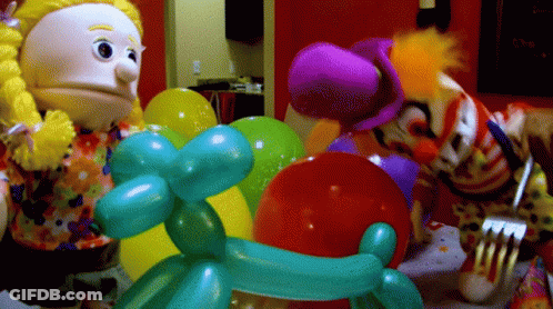 A Clown Is Holding A Fork Next To Balloons GIF