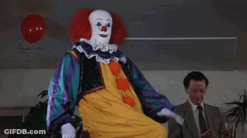 A Clown Is Sitting In Front Of A Man In A Suit . GIF