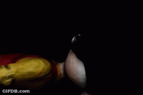 A Clown With A Red Nose Is Laying Down On The Ground GIF