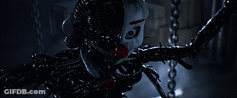 A Clown With A Red Nose Is Tied To A Chain In A Dark Room . GIF