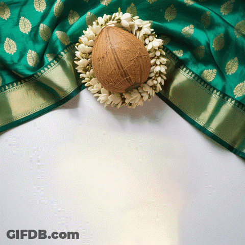 A Coconut Surrounded By White Flowers Sits On A Green Cloth GIF