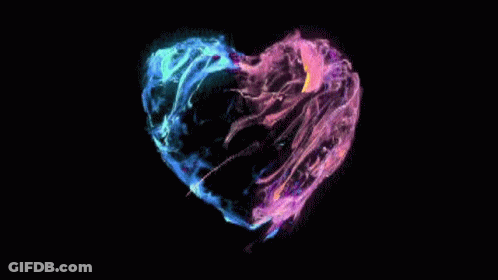 A Colorful Heart Shaped Object Is Floating In The Dark GIF