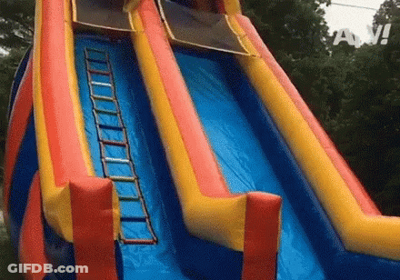 A Colorful Inflatable Water Slide With A Ladder Attached To The Side . GIF