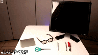 A Computer Monitor Sits On Top Of A White Table With Various Tools And Glasses On It GIF