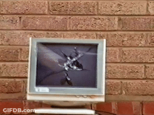 A Computer Monitor With A Broken Screen Is Sitting On A Table In Front Of A Brick Wall GIF