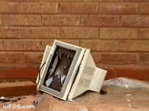 A Computer Monitor With A Broken Screen Is Sitting On The Ground In Front Of A Brick Wall GIF