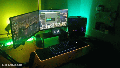 A Computer With Two Monitors And A Clock That Says 11:59 On It GIF