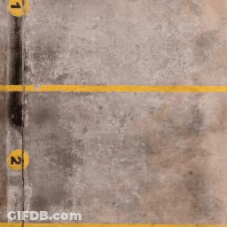 A Concrete Parking Lot With Yellow Lines And Numbers 1 And 2 GIF