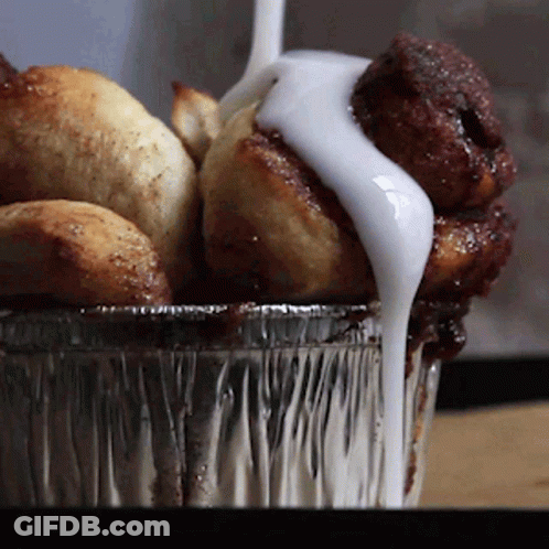 A Container Of Cinnamon Rolls With Icing On Top GIF