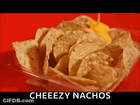 A Container Of Nachos With Cheese Being Poured On Top Of Them . GIF