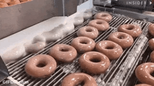 A Conveyor Belt Filled With Doughnuts Being Made In A Doughnut Shop . GIF