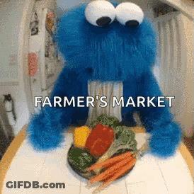 A Cookie Monster Is Sitting At A Table With A Plate Of Vegetables And The Words " Farmer 'S Market " Above It GIF