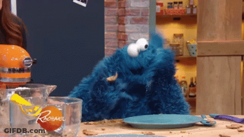 A Cookie Monster Is Sitting On A Kitchen Counter Next To A Measuring Cup That Says Rachael GIF