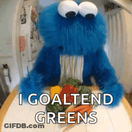 A Cookie Monster Is Sitting On A Table With Vegetables And Says I Goaltend Greens . GIF