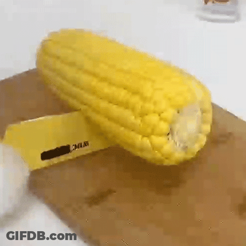 A Corn On The Cob Is Being Peeled On A Cutting Board . GIF