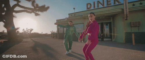 A Couple Dancing In Front Of A Diner That Has The Word Diner On It GIF
