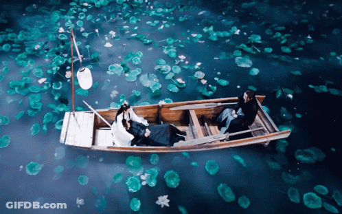 A Couple In A Boat With A Lantern Floating In The Water GIF