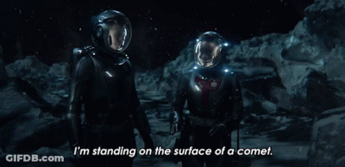 A Couple Of Astronauts Are Standing On The Surface Of A Comet GIF