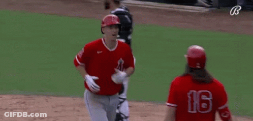 A Couple Of Baseball Players Are Hugging Each Other On A Field . GIF