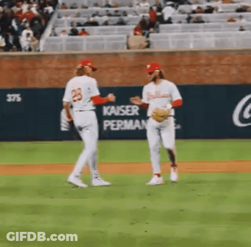 A Couple Of Baseball Players Are Standing On A Baseball Field Talking To Each Other . GIF