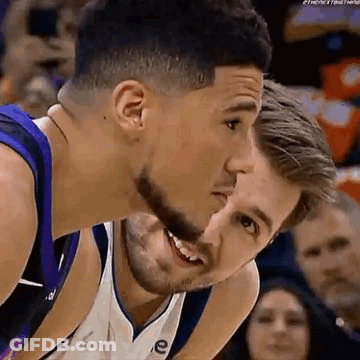 A Couple Of Basketball Players Are Kissing Each Other On The Cheek . GIF
