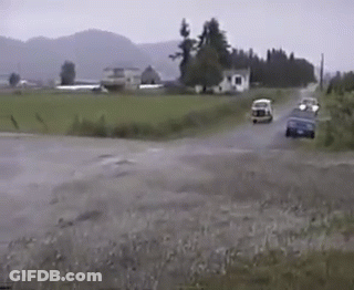 A Couple Of Cars Are Driving Down A Road In The Rain GIF