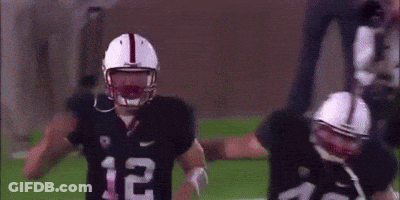 A Couple Of Football Players Are Standing On A Field . GIF
