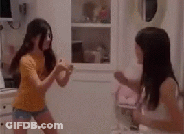 A Couple Of Girls Are Dancing In A Room . GIF