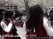 A Couple Of Girls Are Standing Next To Each Other In A Crowded Area . GIF