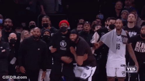 A Couple Of Men Are Hugging Each Other In Front Of A Crowd . GIF