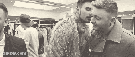 A Couple Of Men Are Kissing In A Room In A Black And White Photo . GIF