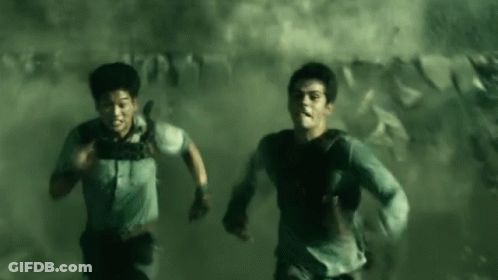 A Couple Of Men Are Running Through A Smokey Room . GIF