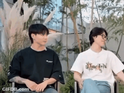 A Couple Of Men Are Sitting Next To Each Other In Chairs . GIF