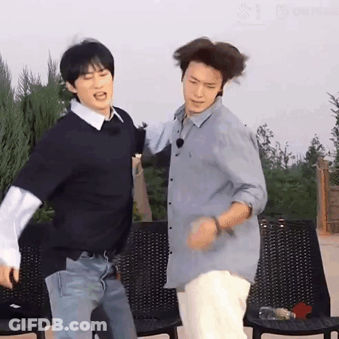 A Couple Of Men Are Standing Next To Each Other And Dancing . GIF