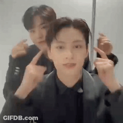 A Couple Of Men Are Standing Next To Each Other And Making Funny Faces With Their Fingers . GIF