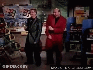 A Couple Of Men Are Standing Next To Each Other And One Is Wearing A Red Jacket . GIF