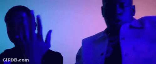 A Couple Of Men Are Standing Next To Each Other In A Dark Room With A Blue Light Behind Them . GIF