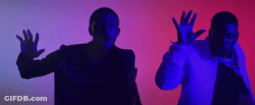 A Couple Of Men Are Standing Next To Each Other In A Dark Room With Their Hands Up In The Air . GIF