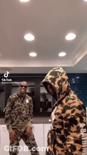 A Couple Of Men Are Standing Next To Each Other In A Kitchen Wearing Camouflage Hoodies . GIF