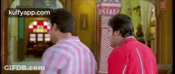 A Couple Of Men Are Standing Next To Each Other In A Room . GIF