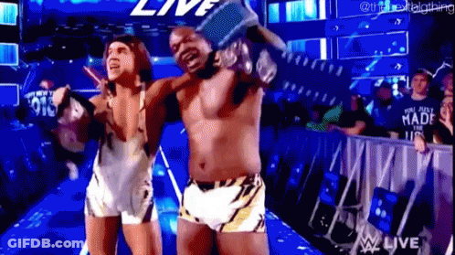 A Couple Of Men Are Standing Next To Each Other In A Wrestling Ring Holding A Trophy . GIF