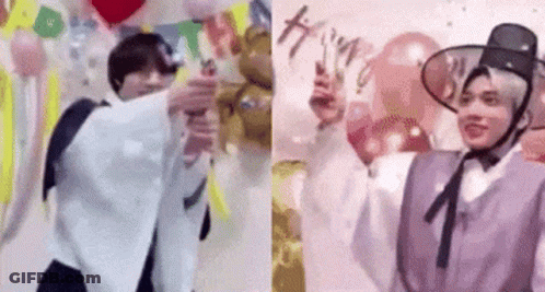 A Couple Of Men Are Standing Next To Each Other In Front Of Balloons And A Wall . GIF