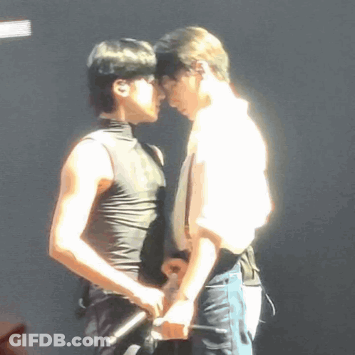 A Couple Of Men Are Standing Next To Each Other On A Stage . GIF