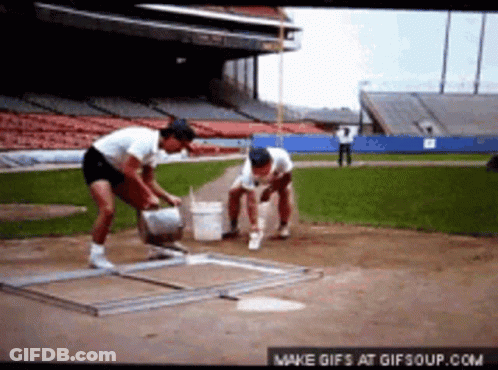A Couple Of Men Are Working On A Baseball Field GIF