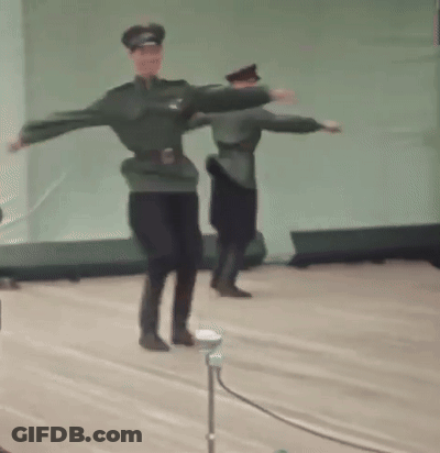 A Couple Of Men In Military Uniforms Are Dancing On A Stage . GIF