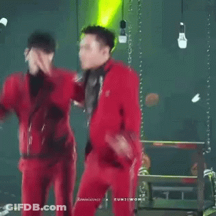 A Couple Of Men In Red Suits Are Dancing On A Stage GIF