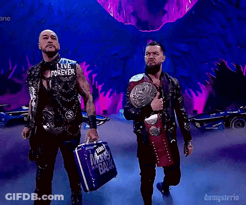 A Couple Of Men Standing Next To Each Other Holding A Briefcase And A Wrestling Belt . GIF