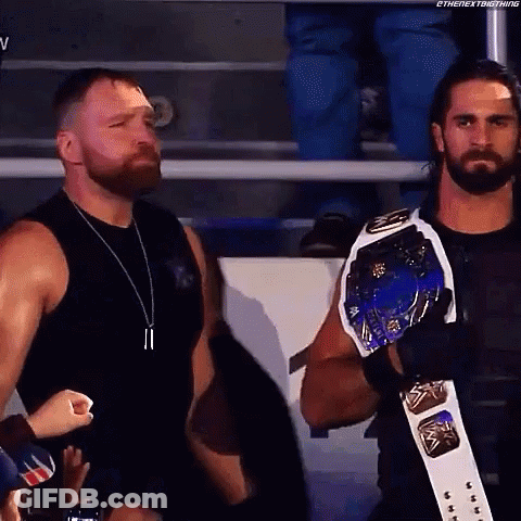 A Couple Of Men Standing Next To Each Other In A Stadium . One Of The Men Is Wearing A Championship Belt . GIF